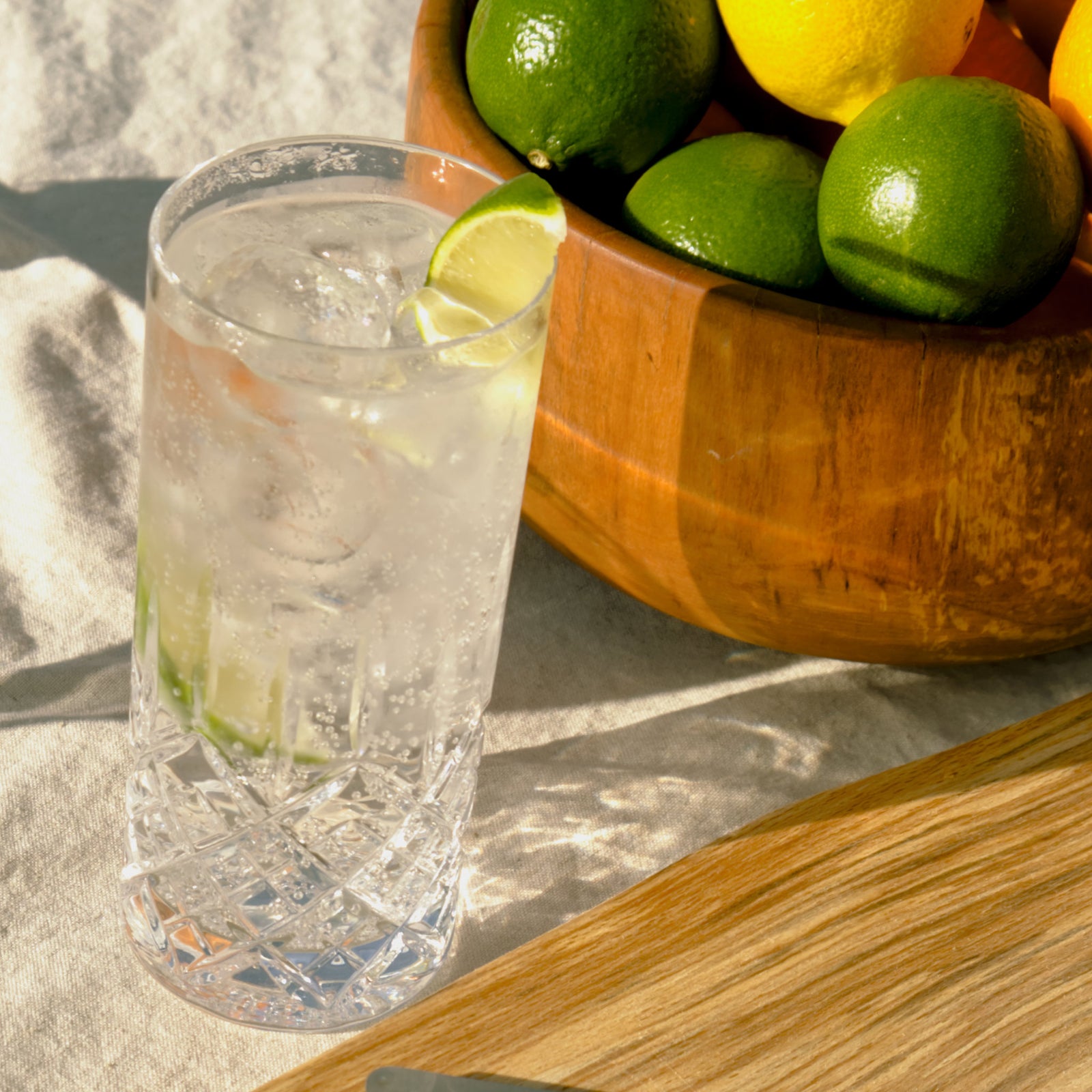 A tall glass of Copper Frog Gin next to a fruit bowl full of citrus fruit.