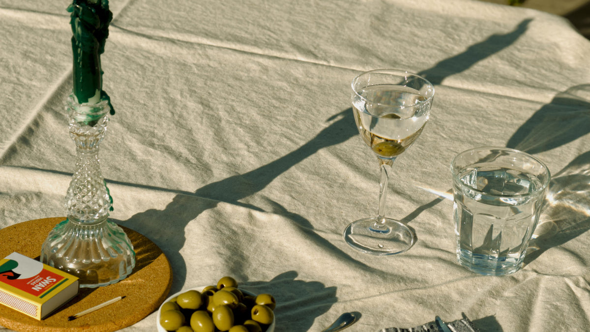 A minimalist table setup with a martini made with Copper Frog Gin served with olives, showcasing the simplicity and elegance of Good Natured Spirits. 