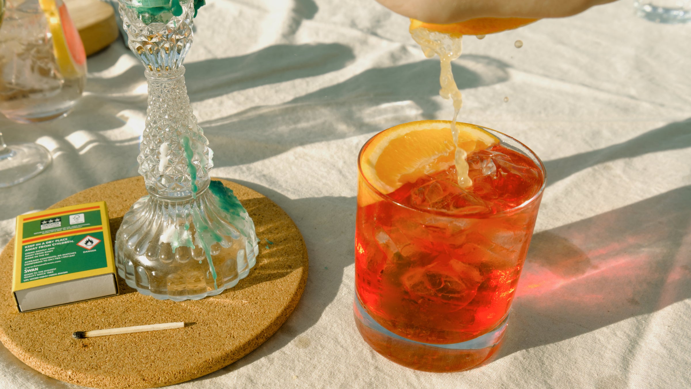 An orange slice being squeezed into a vibrant negroni cocktail, emphasising the fresh, zesty flavours of Devon Gin and the natural ethos of Good Natured Spirits.